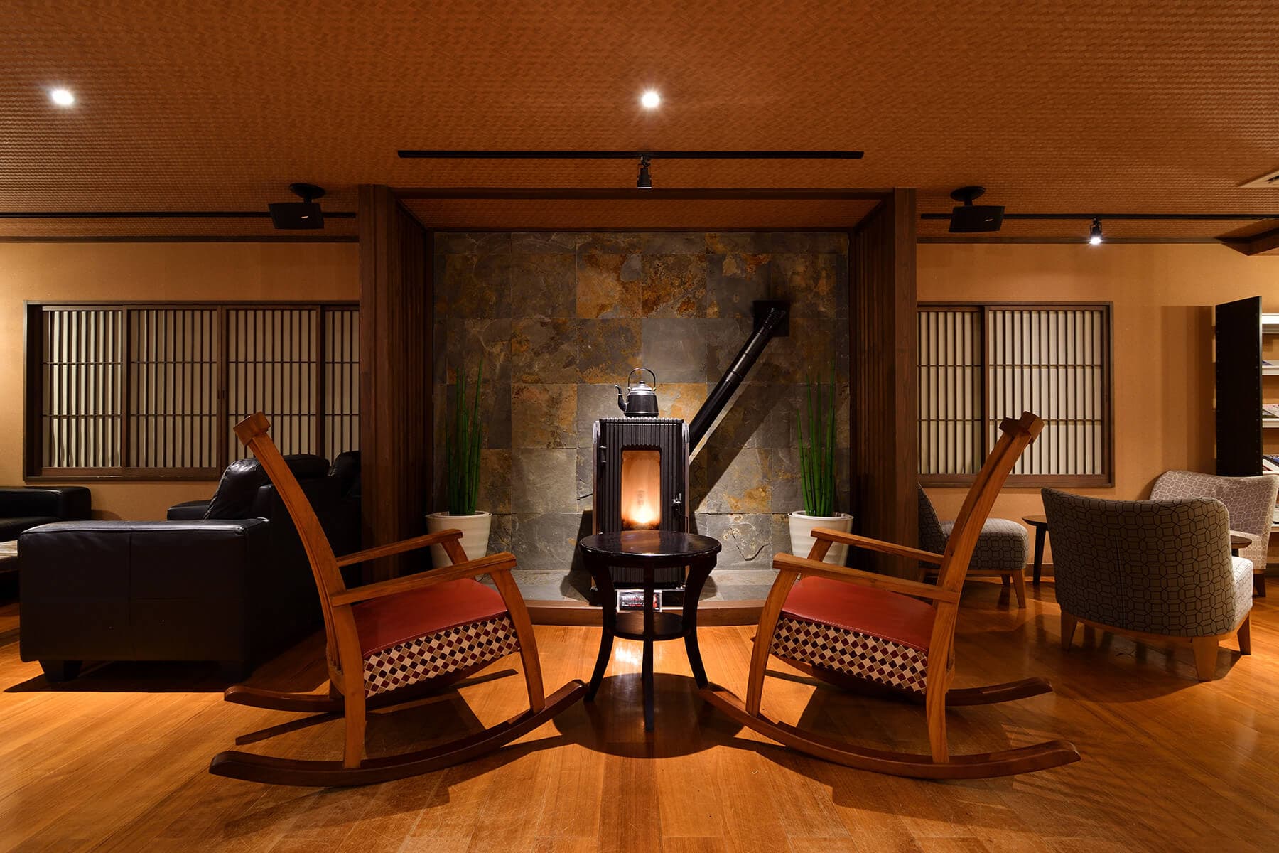 Cozy wood-floored lounge with a cast-iron stove, rocking chairs and shoji screens