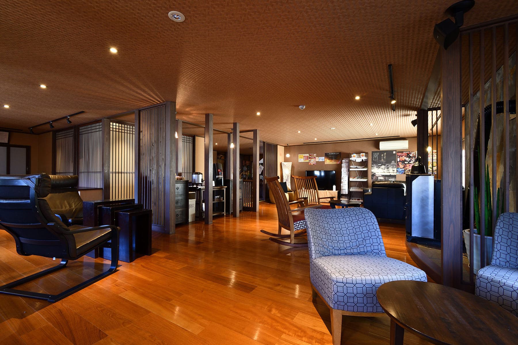 Spacious open lounge area with polished wood flooring, lounge chairs and warm lighting