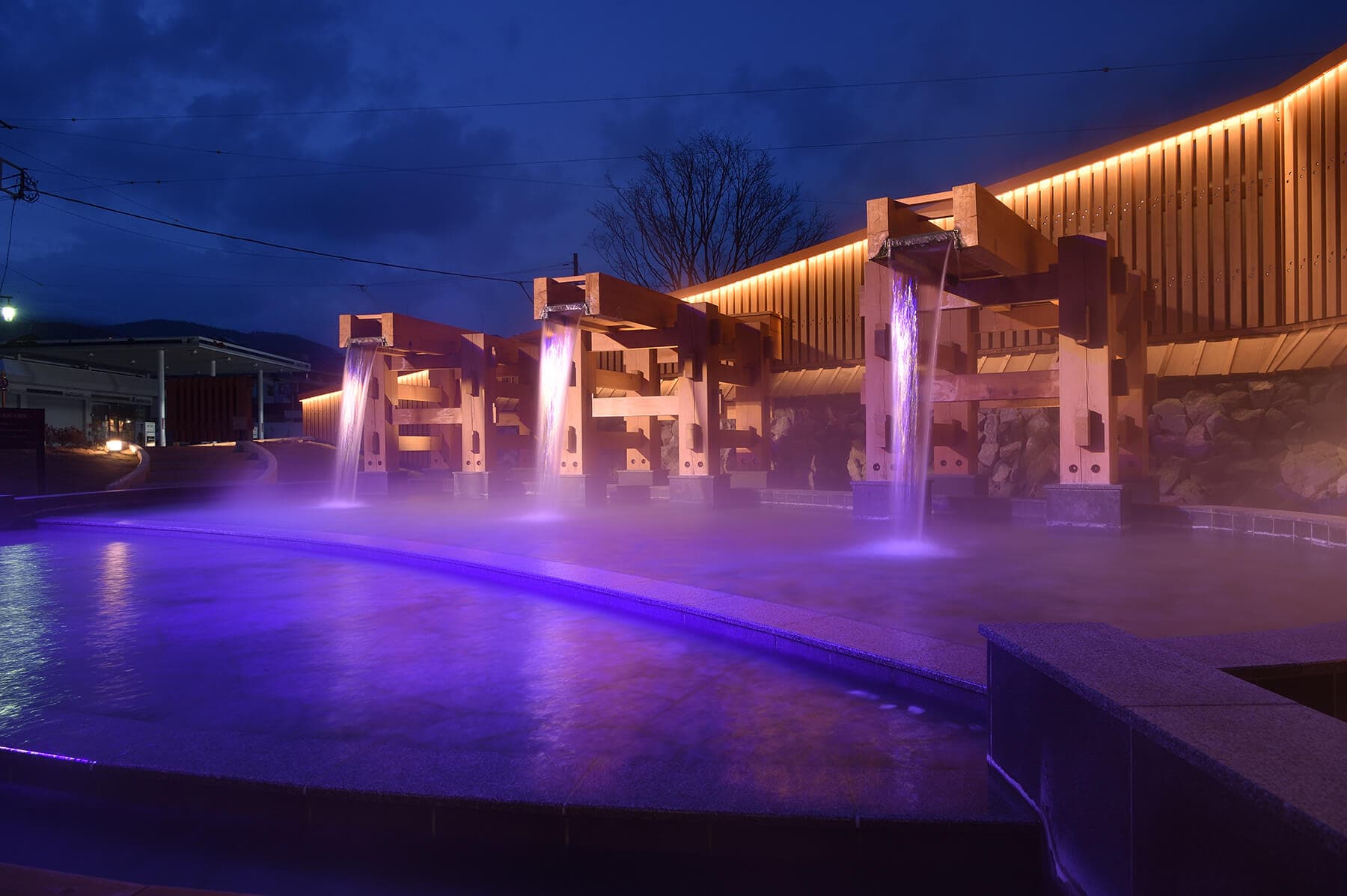 Illuminated cascading hot-spring water feature and steaming pool at dusk in Kusatsu Onsen