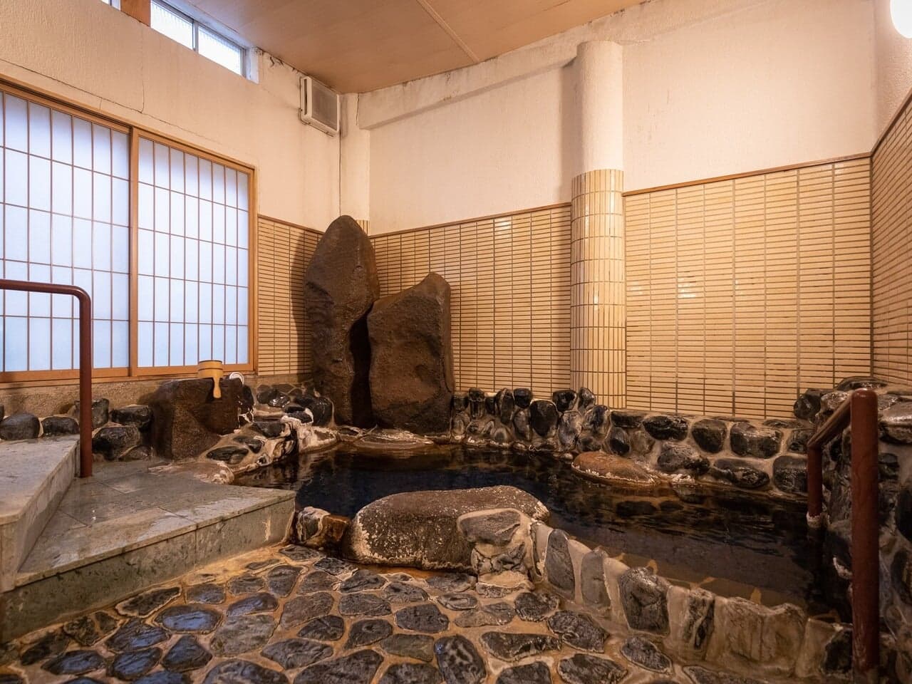 Indoor uchiyu bath built from natural stone with bamboo walls at Yumoto Tamaikan ryokan