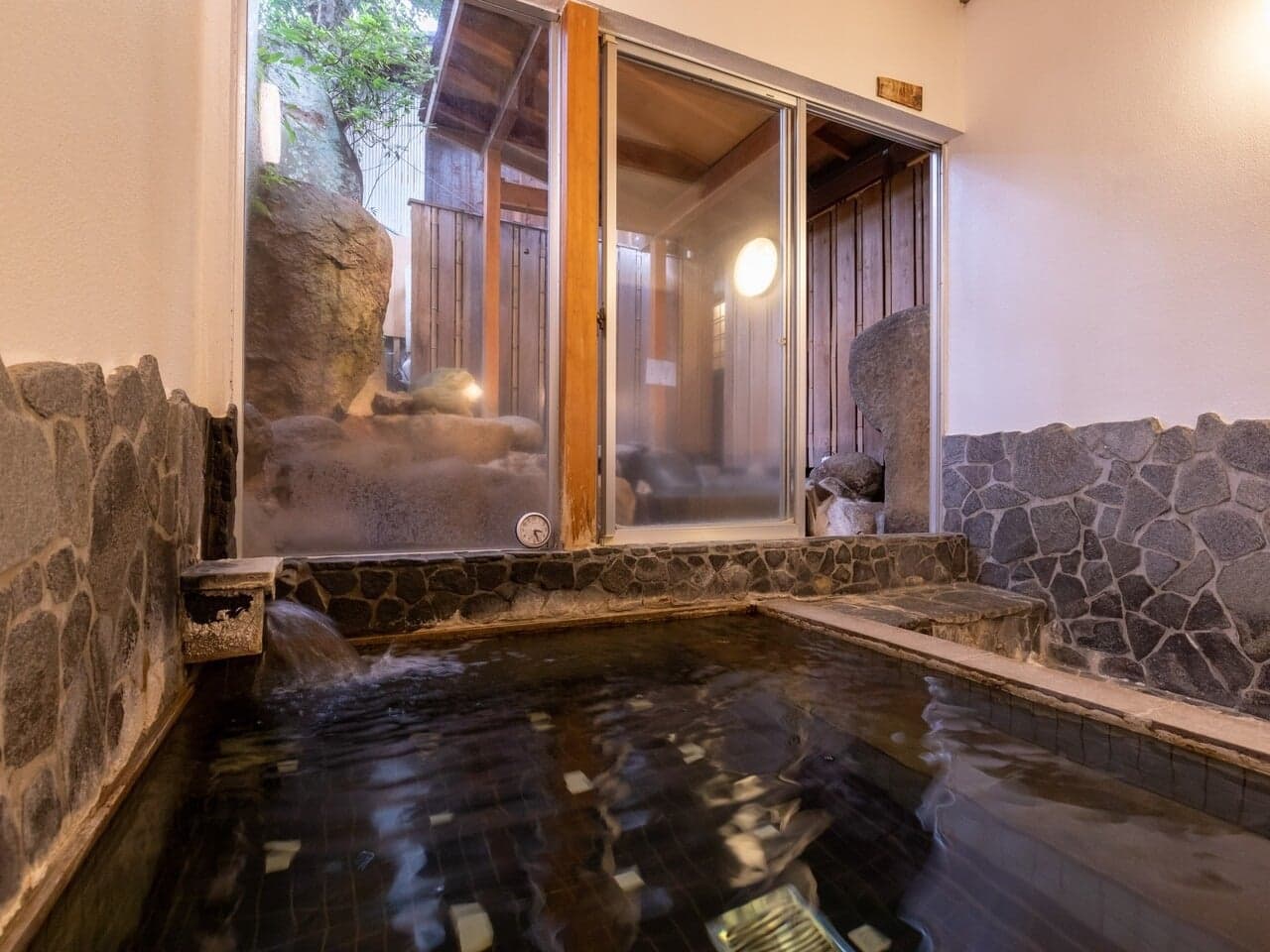 Steamy indoor stone hot-spring bath with a garden view at Yumoto Tamaikan, Tamatsukuri Onsen
