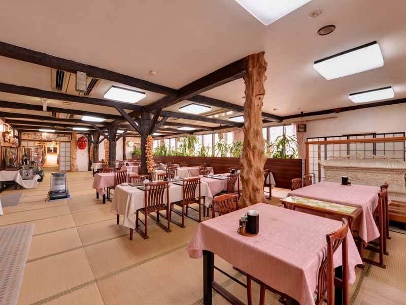 Spacious tatami dining hall with a carved log pillar and forest-view windows