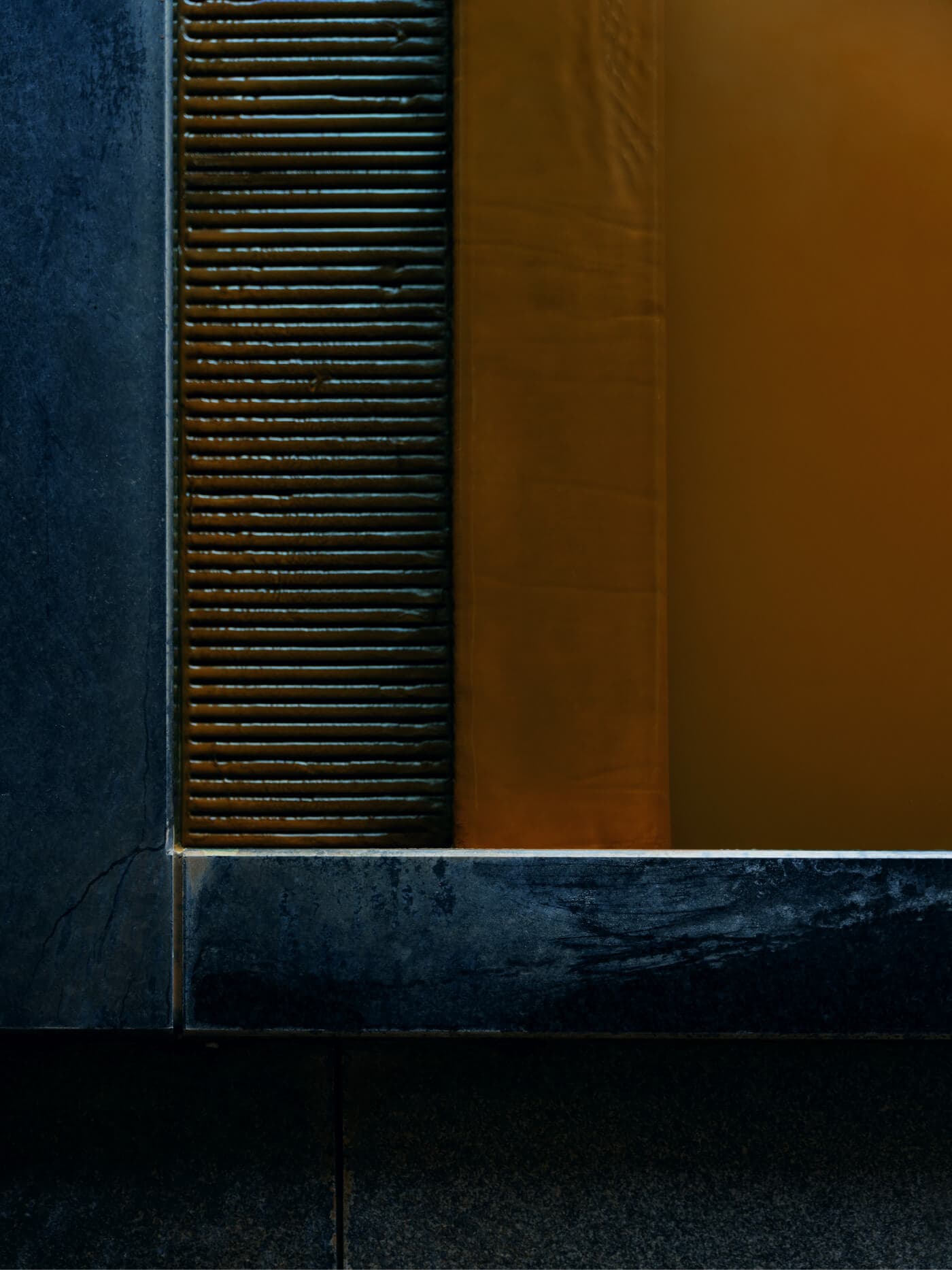 Reddish-brown kinsen gold-spring bath at dusk with a panoramic window overlooking the lit Arima Onsen townscape and mountains at Takayamaso Hanano