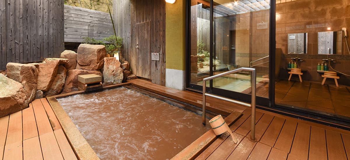 Koki outdoor kinsen rotenburo open-air bath with reddish-brown Arima gold-spring water, rocks and wooden deck