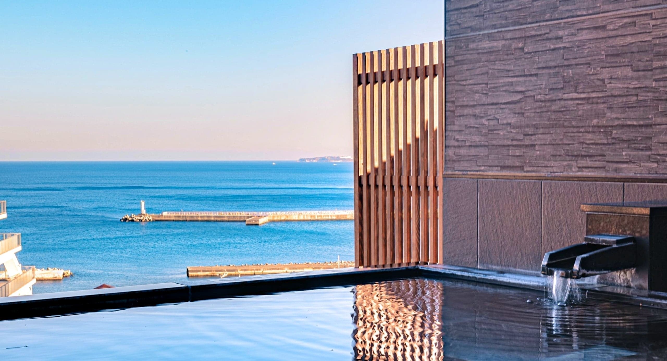 Open-air bath at Hotel Kanichi overlooking the calm sea at Atami Onsen