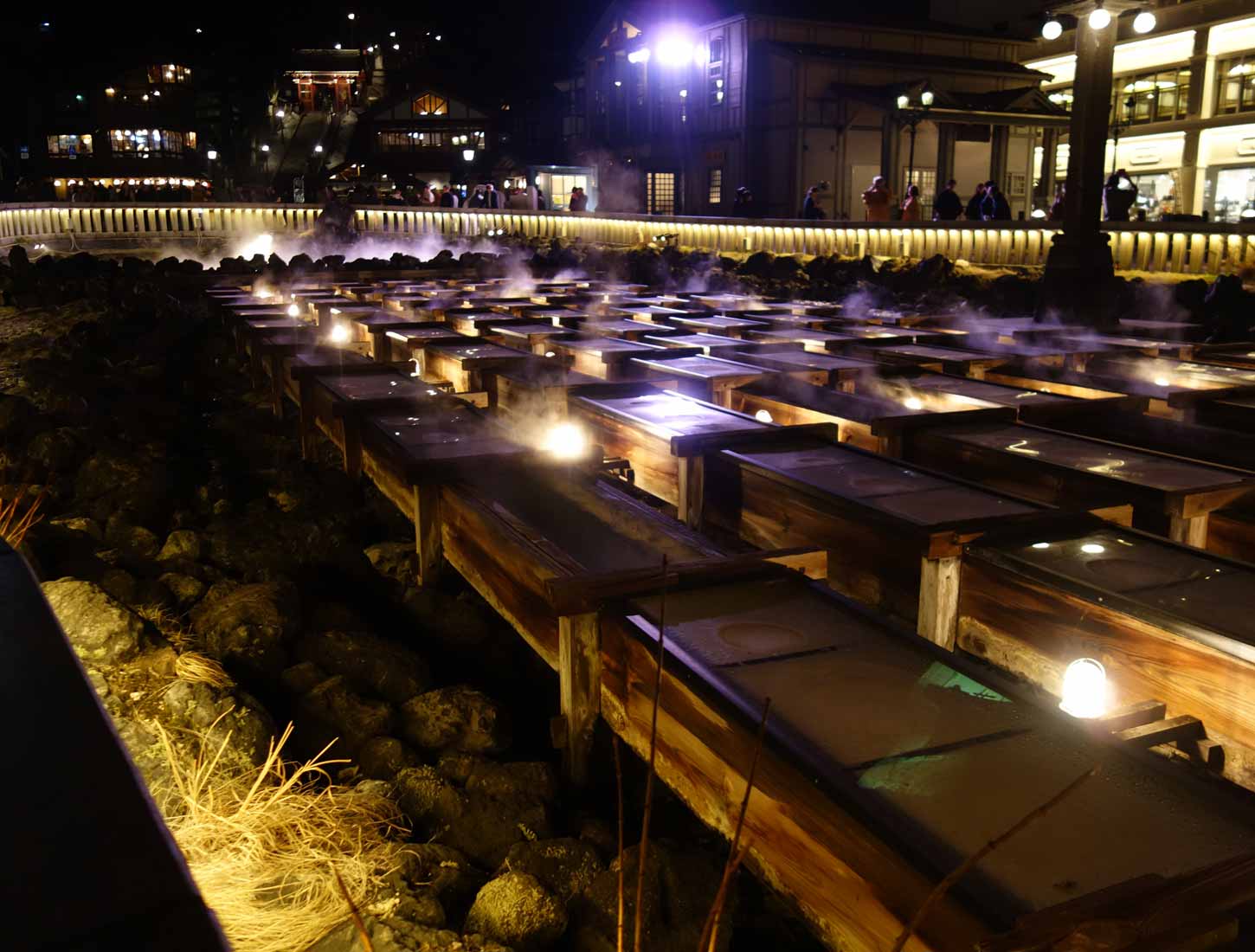 Kusatsu Yubatake hot-water field glowing with steam and lanterns at night nearby