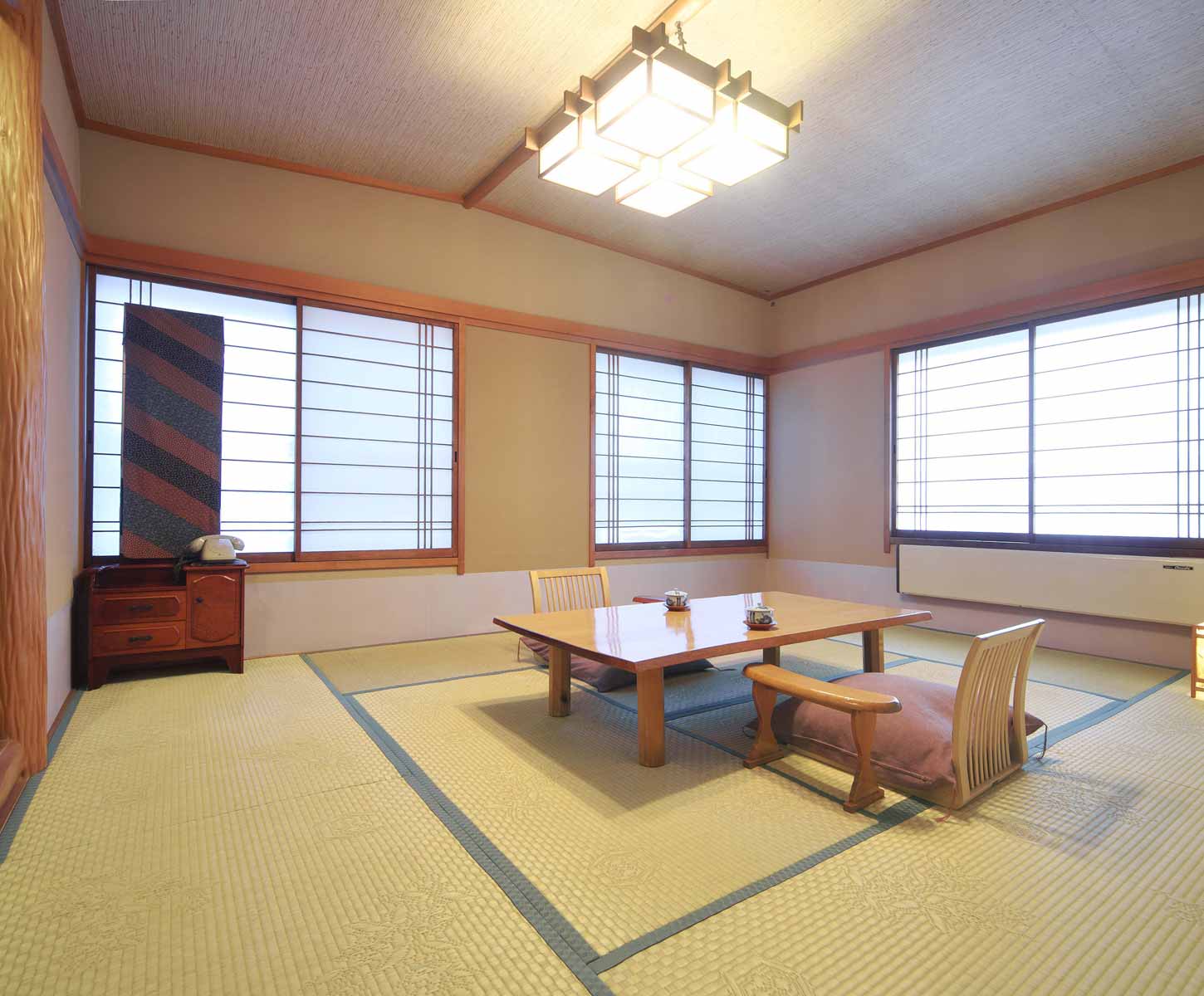 Spacious tatami guest room with low table, floor chairs and shoji-screened windows