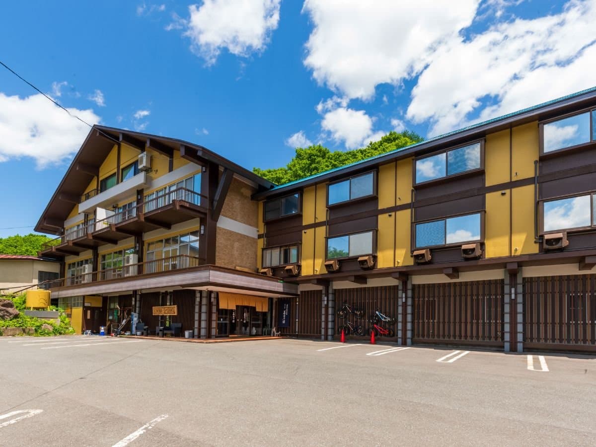 Mogamitakayu Zenshichinoyu Ohira ryokan exterior, wooden three-storey building under blue sky at Zao Onsen