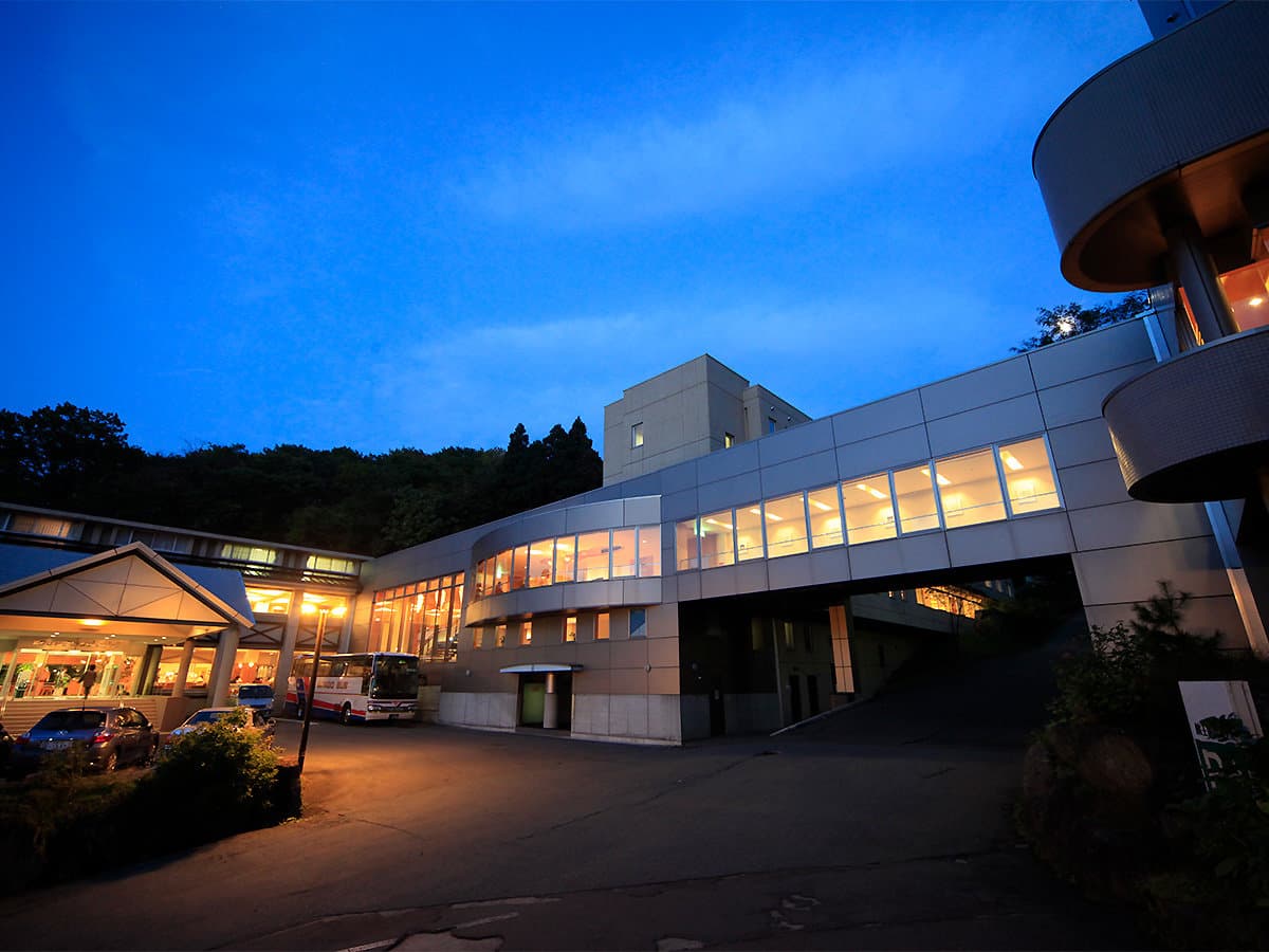 Zao Kokusai Hotel exterior glowing at dusk under a deep blue sky at Zao Onsen, Yamagata
