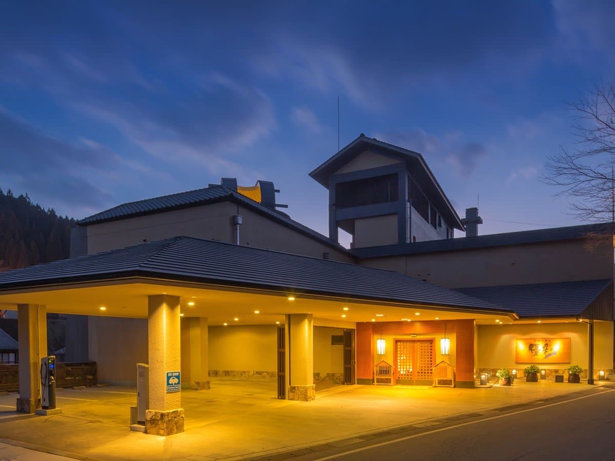 Yukyo no Hibiki Yusai grand main building exterior with lantern-lit porte-cochere entrance at dusk, Kurokawa Onsen