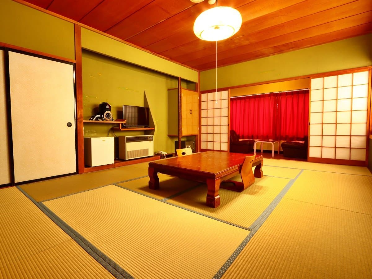 Bright tatami room with green walls, a low table and a window lounge area behind a red curtain