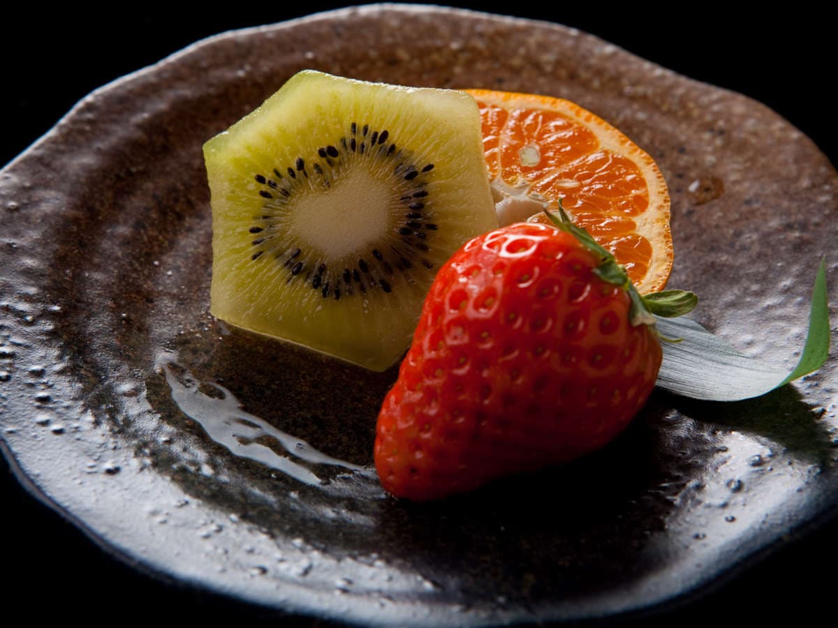 Fresh fruit dessert of kiwi, mandarin orange and strawberry on a dark glazed ceramic plate, Ryokan Sennari, Beppu Onsen