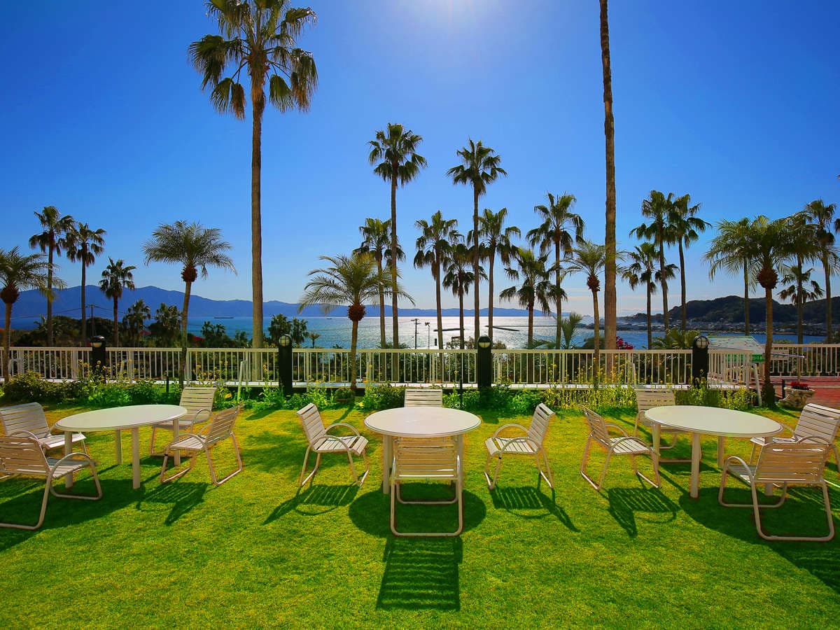 Palm-lined garden lawn terrace at Ibusuki Phoenix Hotel with patio seating overlooking the bay