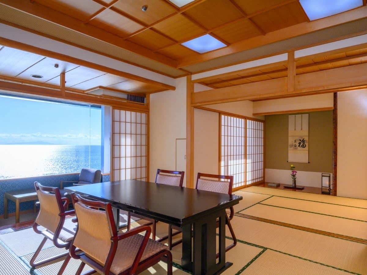 Spacious Japanese tatami guest room with low table and panoramic Atami ocean view