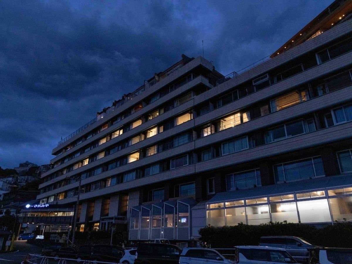 Hotel New Sagamiya full building exterior lit up at dusk above Atami Onsen on the Izu coast