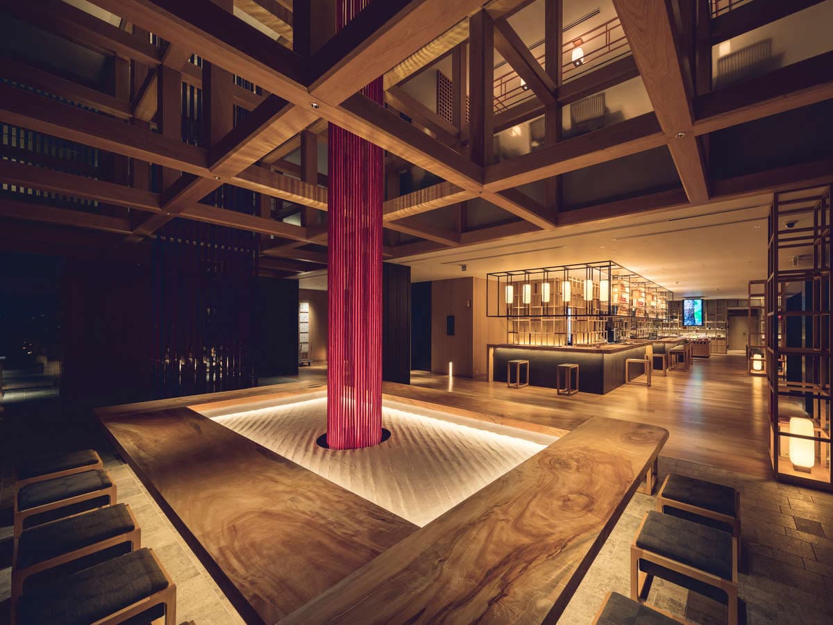Timber-framed lobby atrium with a hanging red-thread art installation and raked sand at Tokyu Stay Hida Takayama