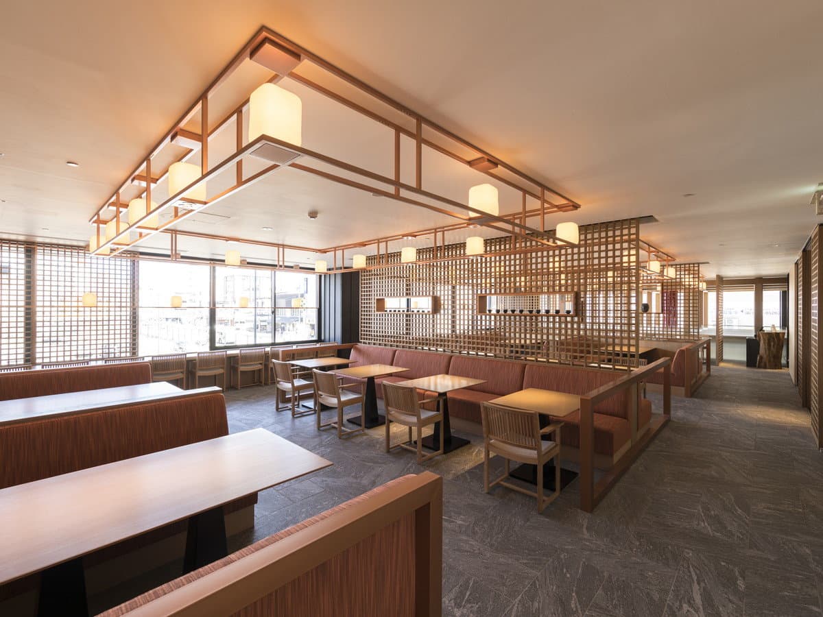 Restaurant dining hall with banquette seating, wooden lattice screens and lantern-style light fixtures