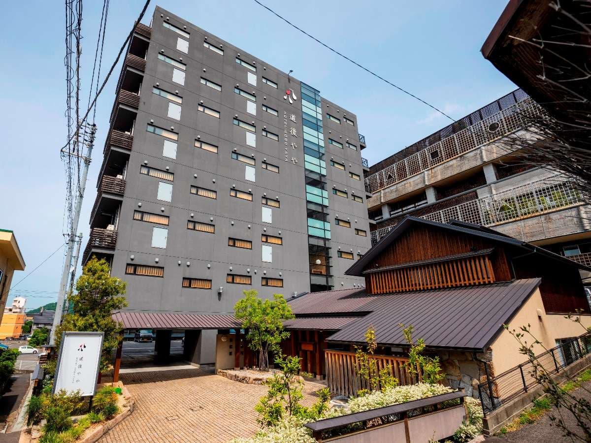 Daytime exterior of Hotel Dogo Yaya showing the tall main building and wooden entrance pavilion