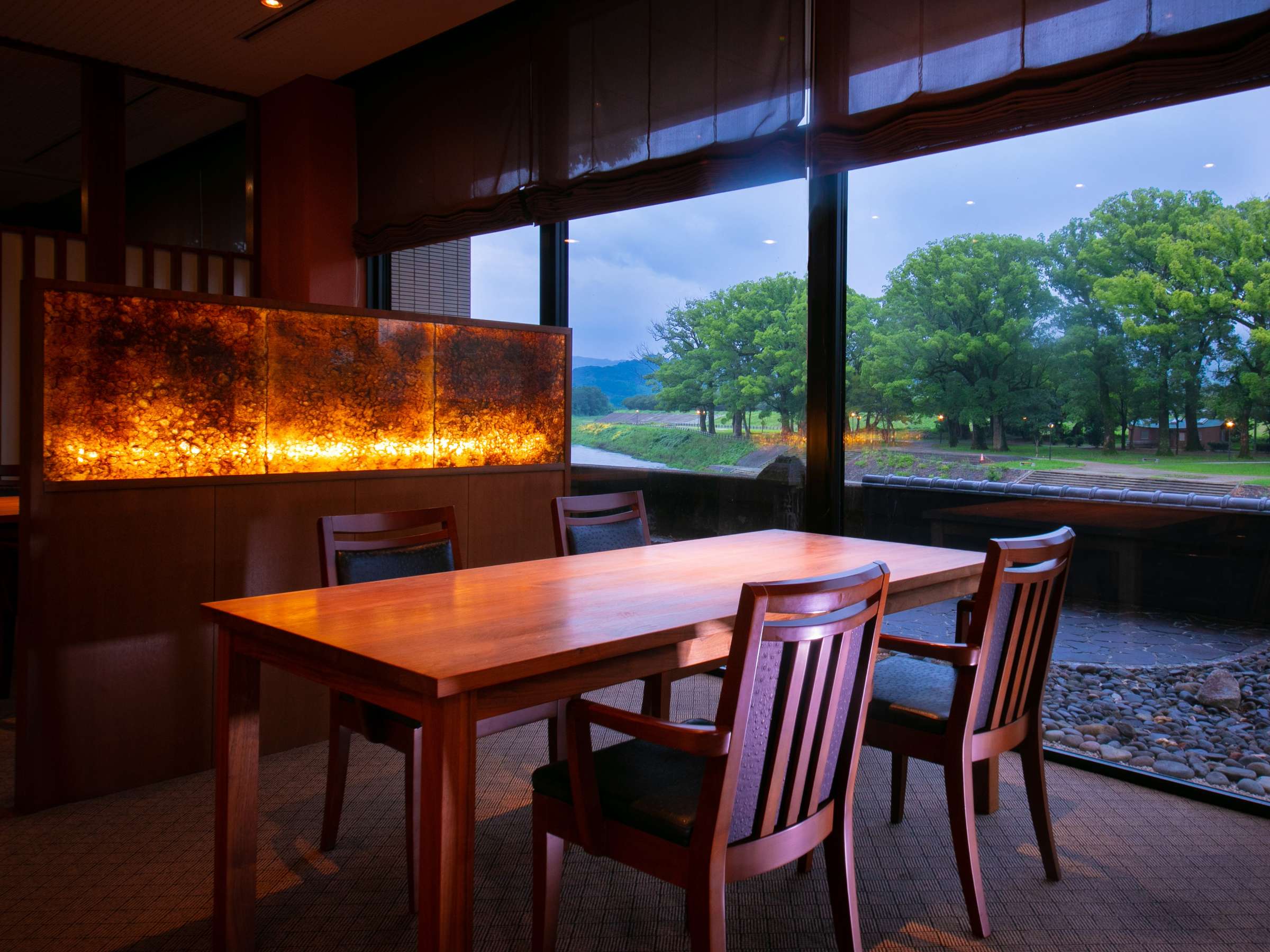 Private riverside dining room with wooden table and dusk view over the Yabe River at Hotel Higuchiken