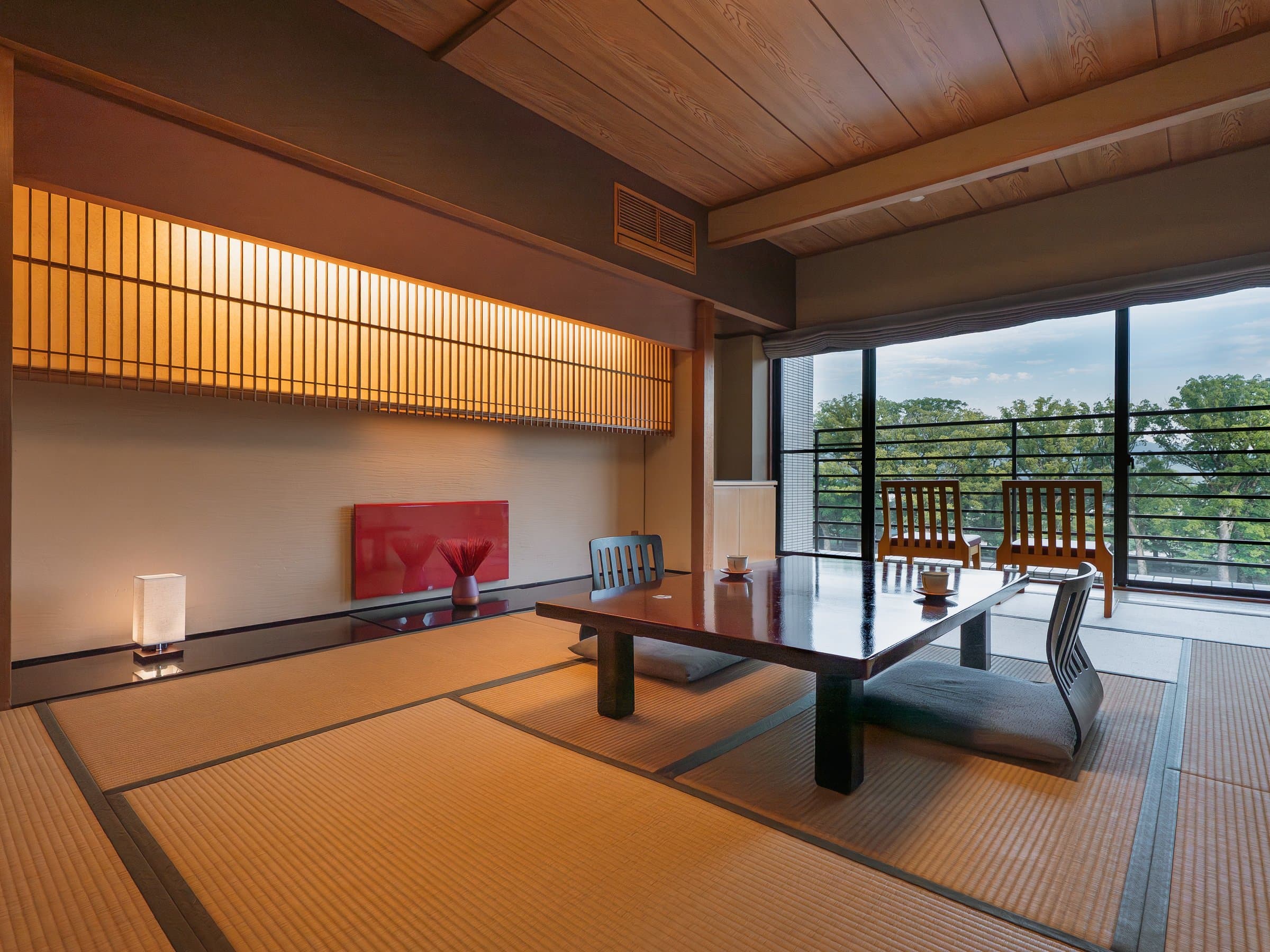 Japanese-modern guest room with low table and private river-view balcony at Hotel Higuchiken
