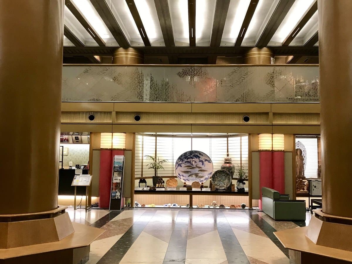 Lobby entrance hall with decorative Japanese porcelain display and tall columns at Miyajima Hotel Makoto