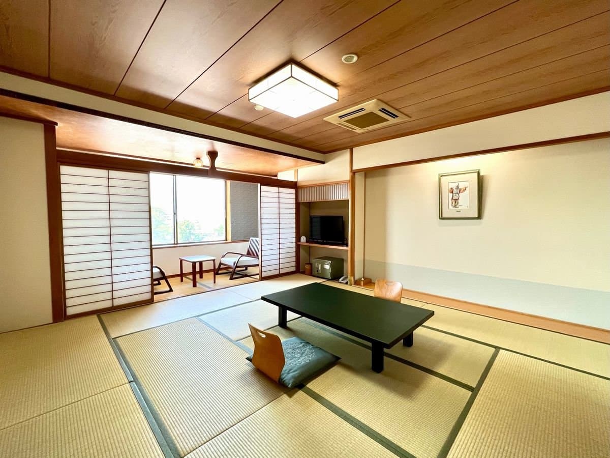 Spacious Japanese-style tatami guest room with low table and shoji windows at Miyajima Hotel Makoto