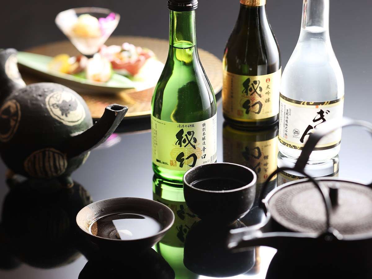 Local Gunma sake bottles and cups arranged beside a kaiseki appetizer plate at Hotel Sakurai