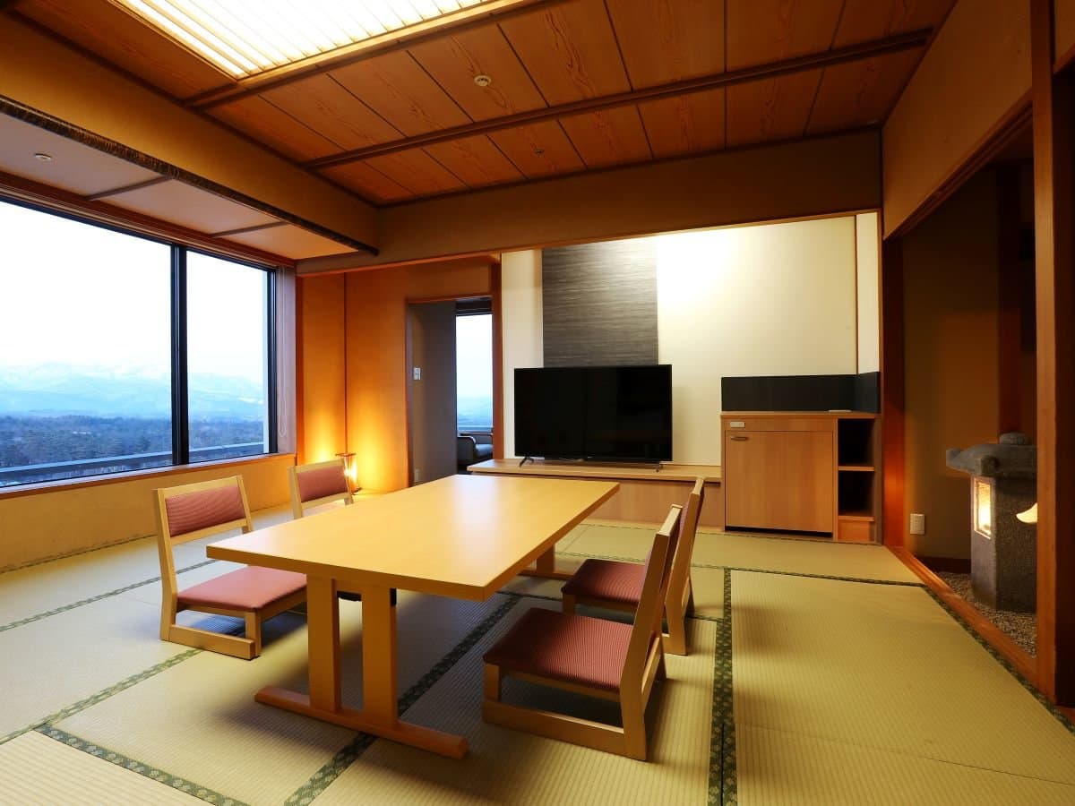 Standard Japanese-style tatami guest room at Hotel Sakurai with a low lacquer table and large windows framing the surrounding mountains