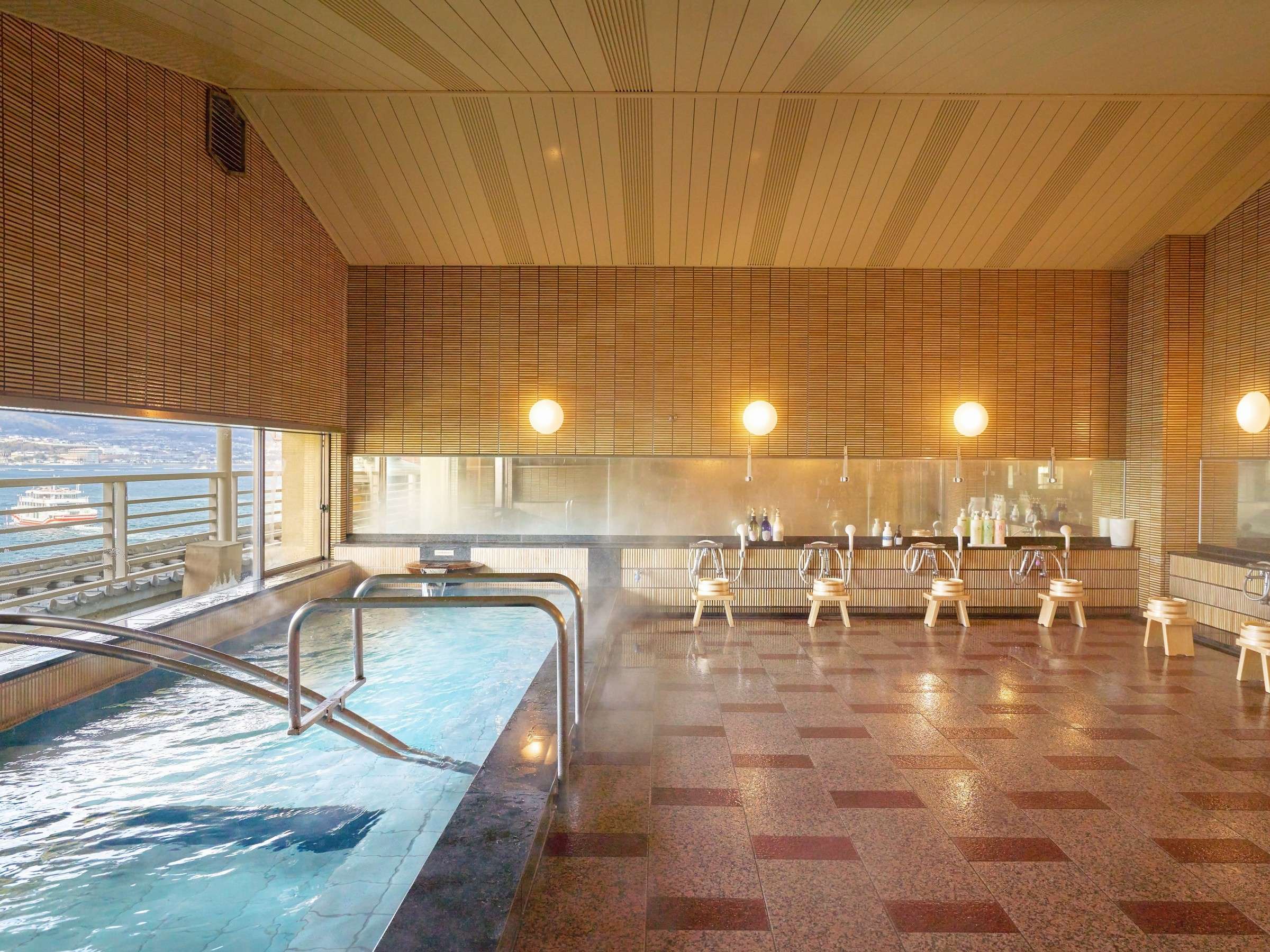 Steaming indoor onsen bath at Hotel Miyarikyu with large windows facing the Seto Inland Sea on Miyajima