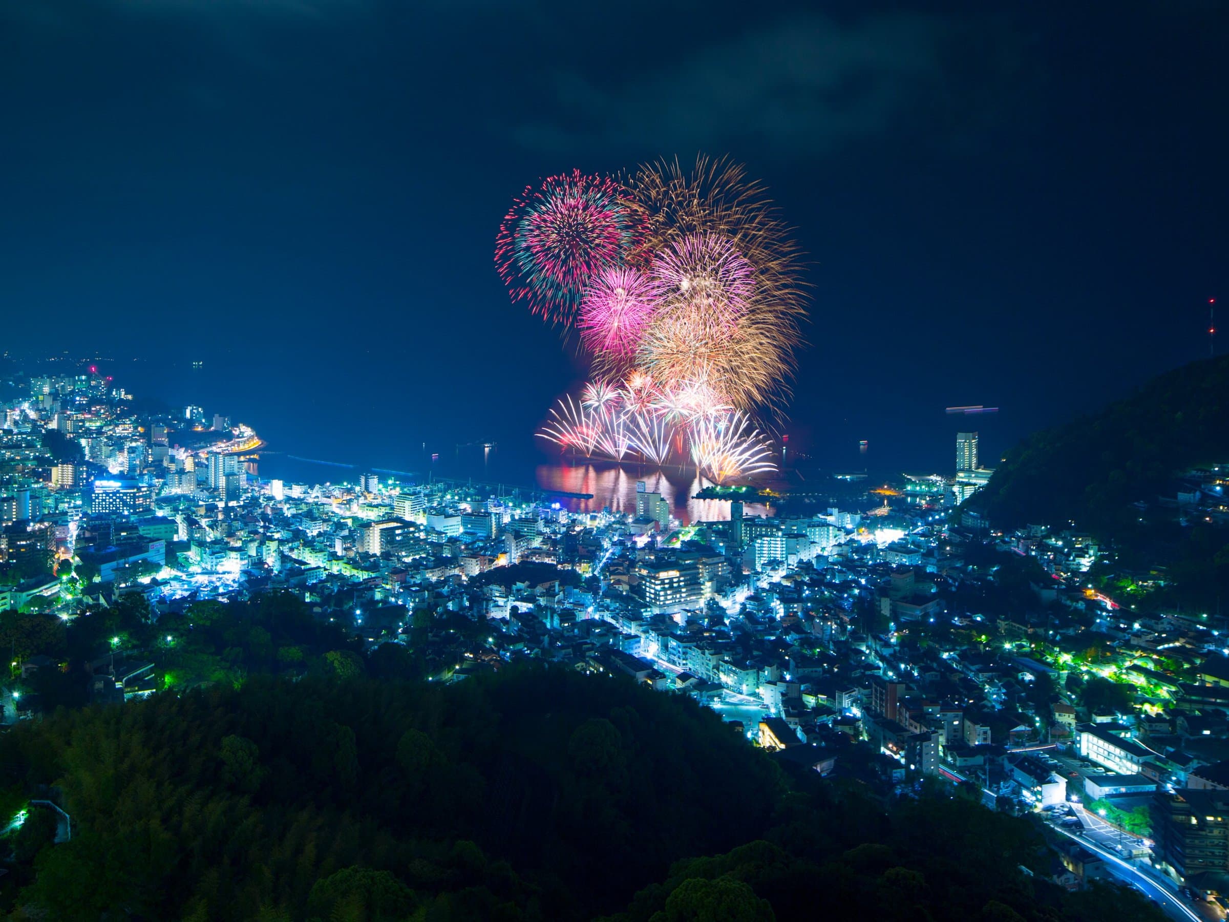 Atami summer fireworks bursting over the bay and hillside city lights near Risonare Atami