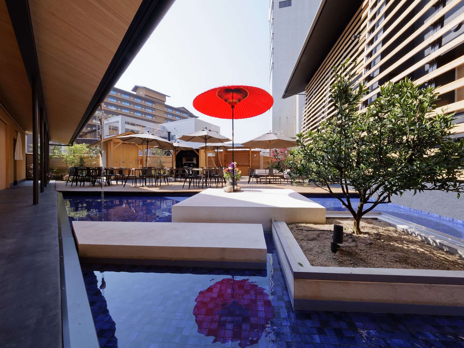 Courtyard water garden with a red Japanese parasol and olive tree at Koto no Niwa, Dogo Onsen