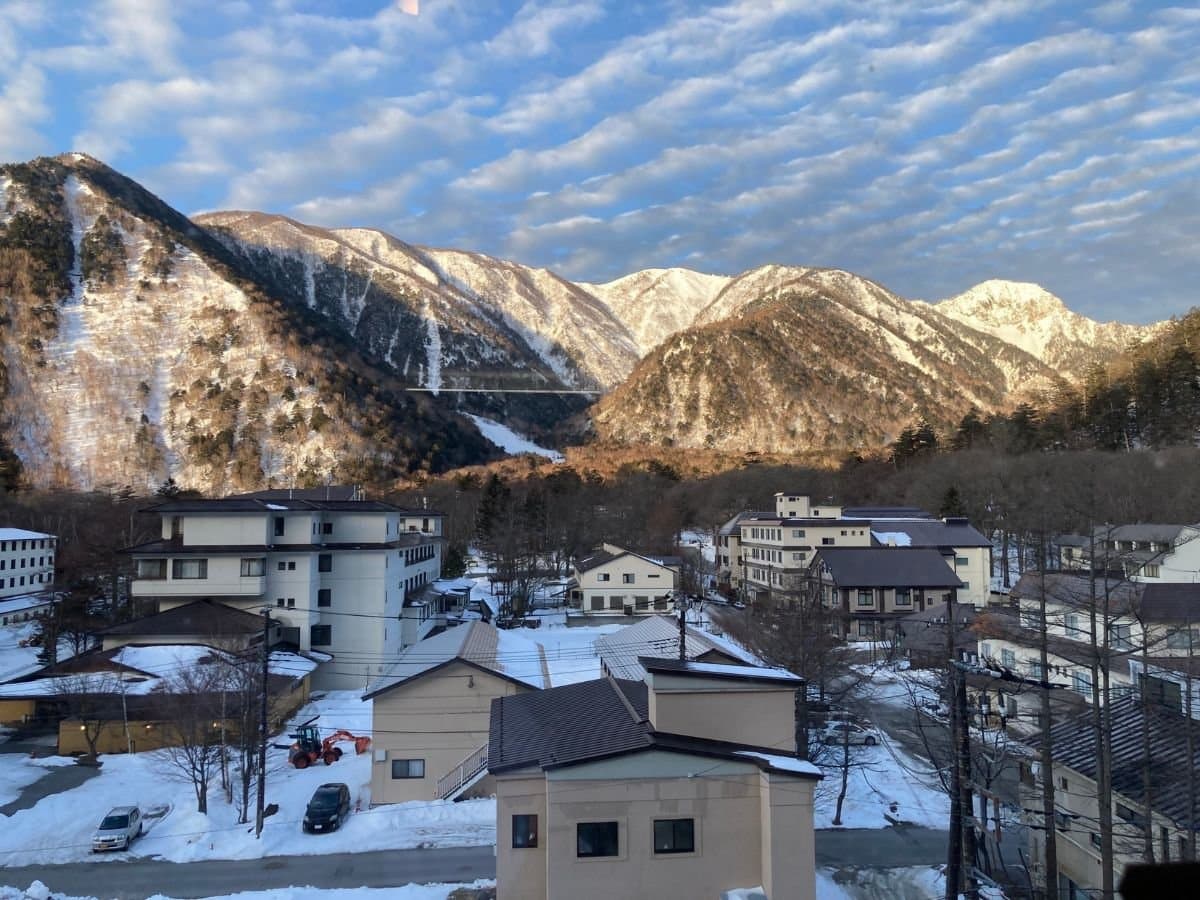 View over Okunikko Yumoto Onsen town and snow-capped mountains from Yumoto Itaya