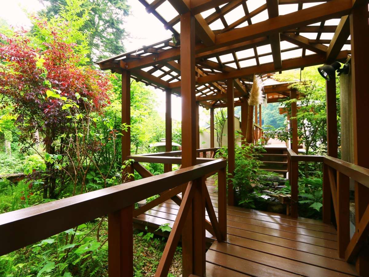 Covered wooden walkway winding through the lush garden of Oyado Yamashita, Yuwaku Onsen near Kanazawa