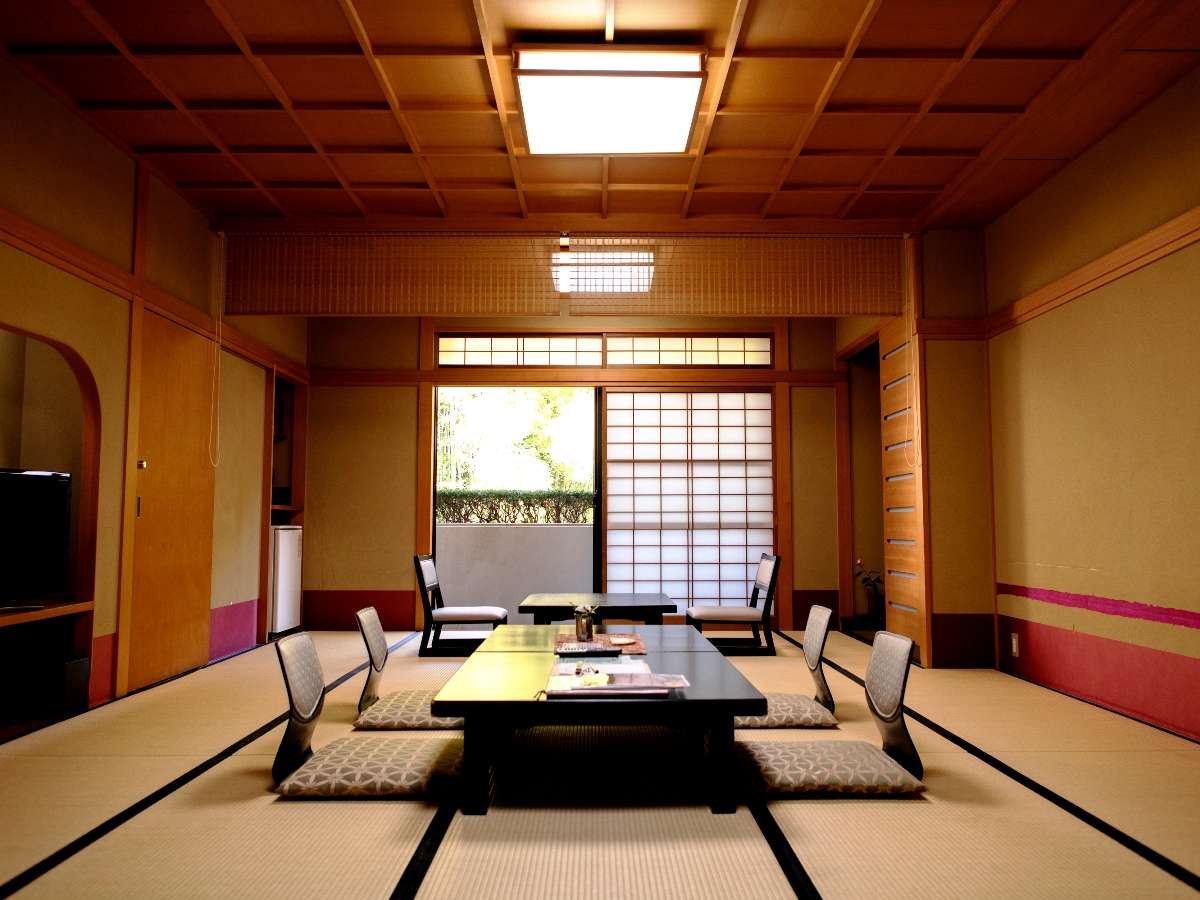 Spacious tatami guest room with low table and shoji screens opening to greenery at Oyado Yamashita, Yuwaku Onsen