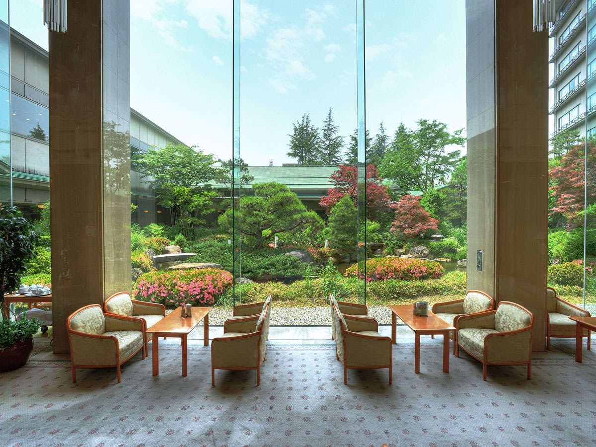 Takayama Green Hotel lobby lounge with armchairs facing a manicured Japanese garden through floor-to-ceiling glass