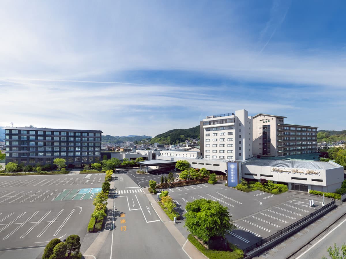 Aerial view of Takayama Green Hotel's full exterior and grounds under a blue sky in Hida Takayama