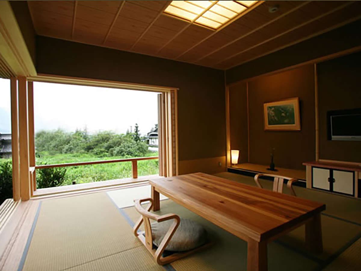 Tatami guest room at Yufuin Hoteiya with low wooden table opening onto a green countryside view