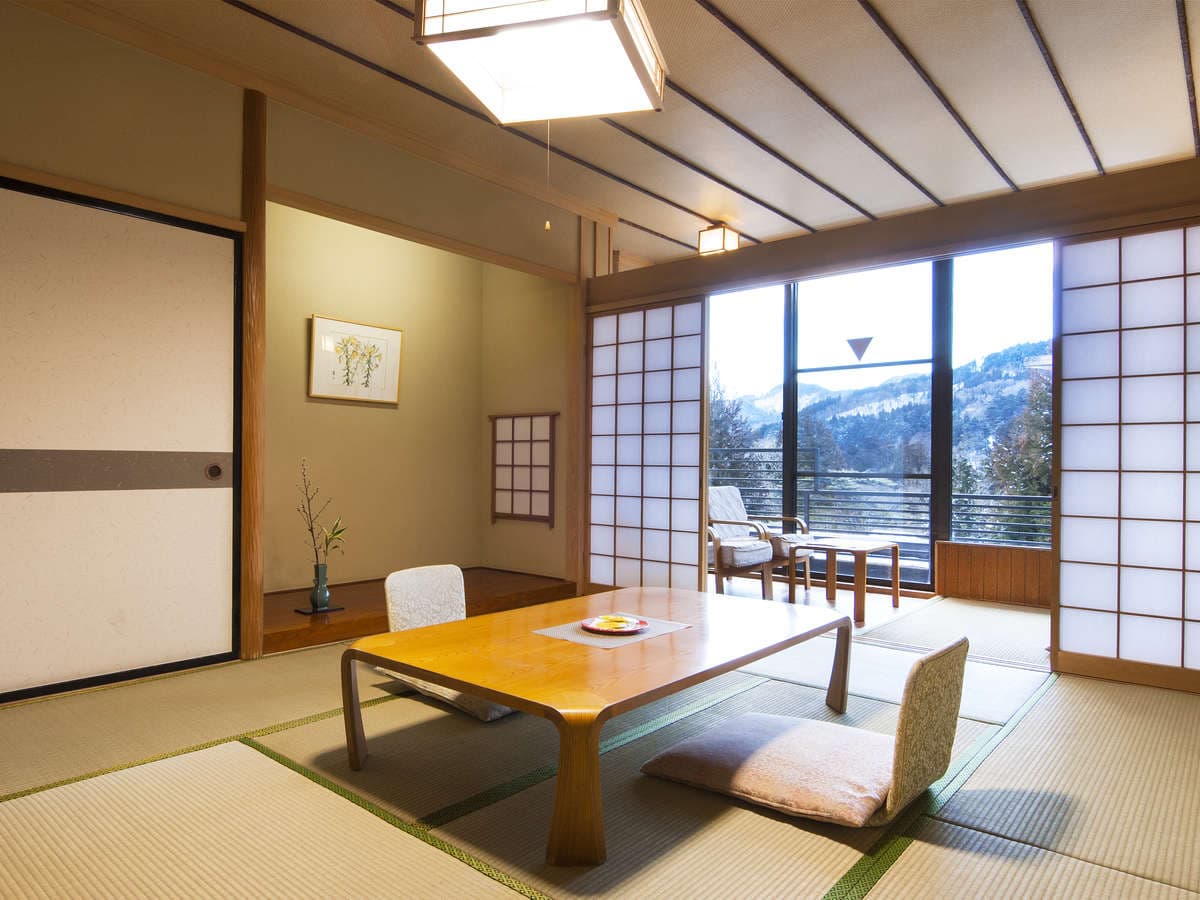 Spacious Japanese-style tatami guest room with tokonoma alcove and wide window overlooking Nikko's wooded mountains