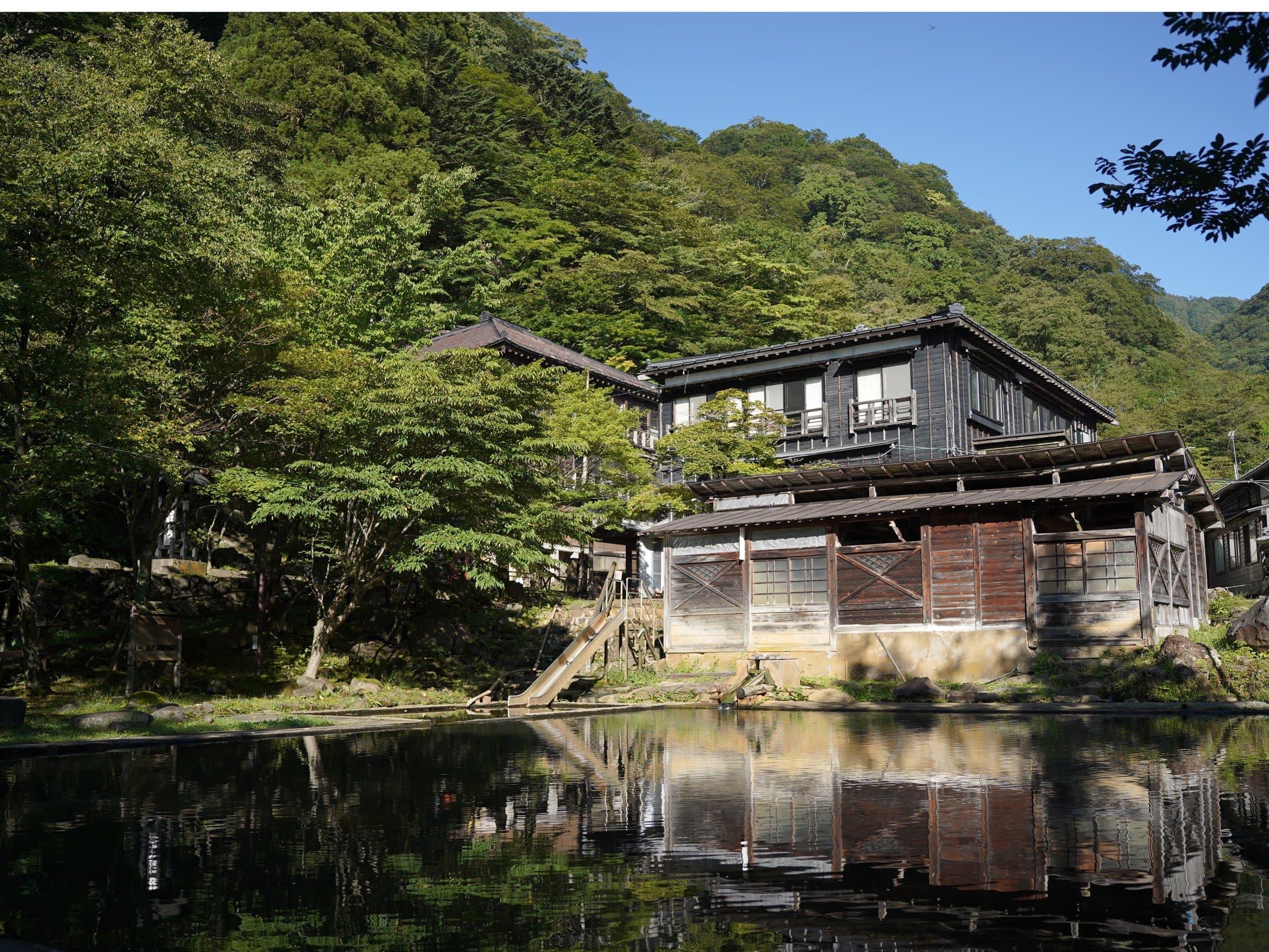 Rustic wooden inn reflected in the hot spring pond