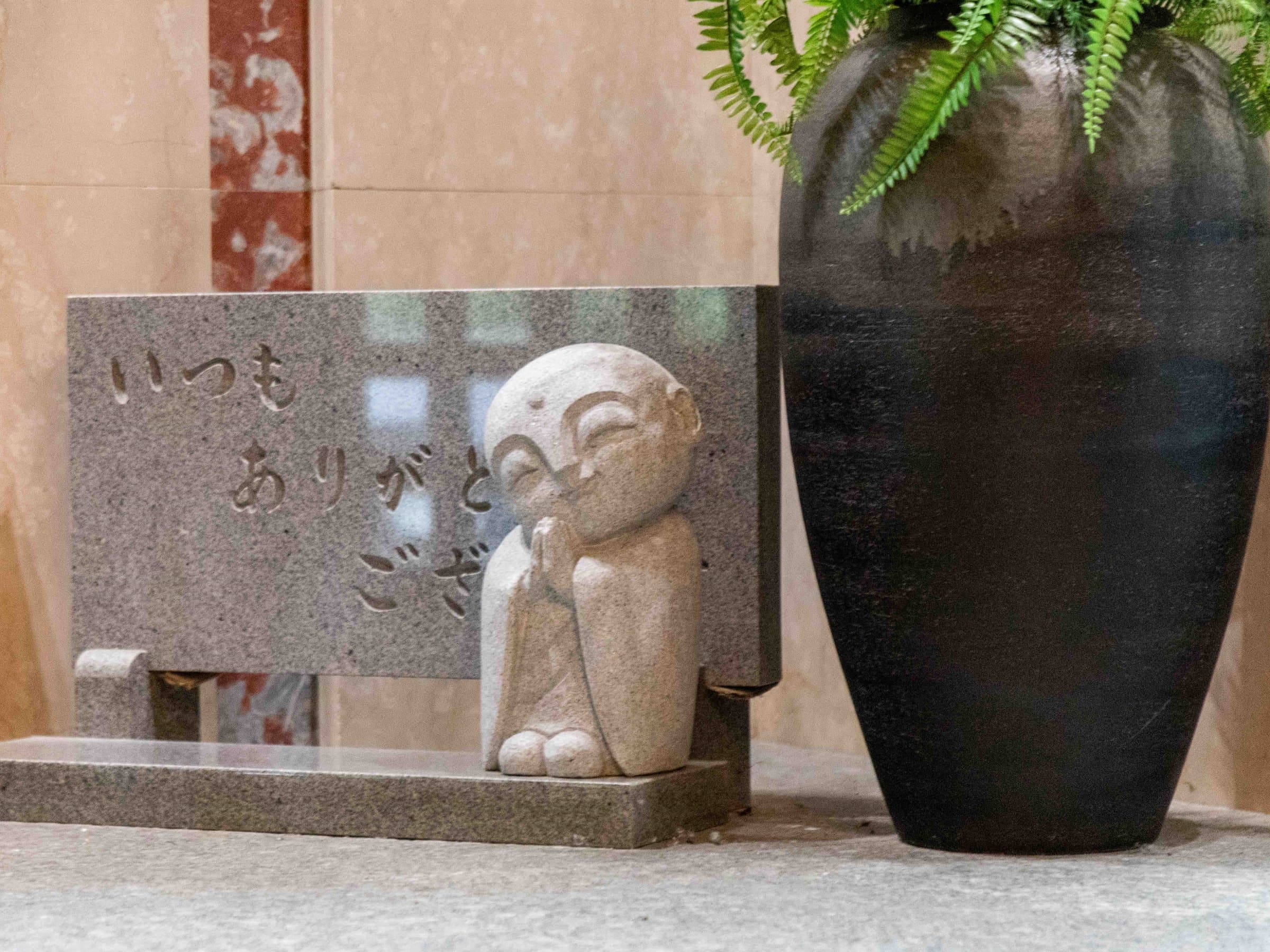 Suizanso Kinosaki Onsen entrance detail with stone jizo statue and ceramic vase