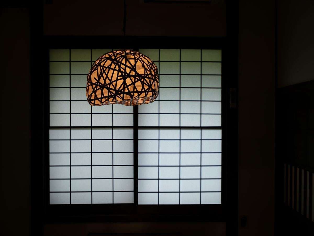 Architectural detail at Fujiya: a woven bamboo pendant lamp glowing against a backlit shoji screen