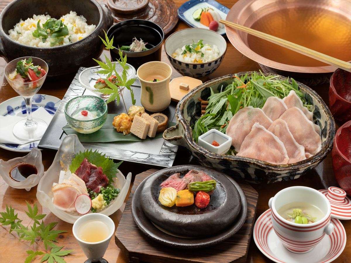 Kaiseki dinner spread at Fujiya with a pork-and-vegetable hotpot, grilled meat on a hot stone, sashimi, rice and assorted small dishes