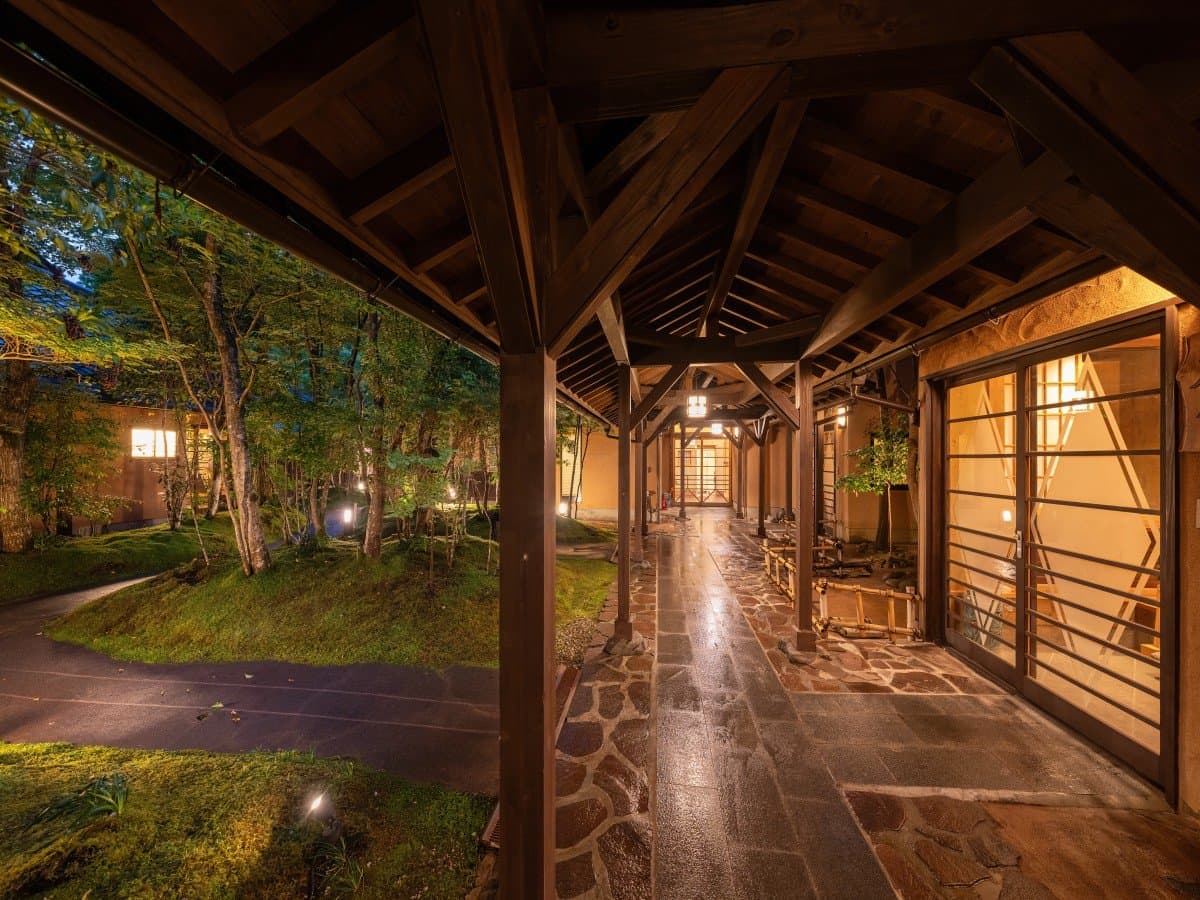 Oyado Nonohana covered wooden entrance walkway lit by lanterns at dusk in Kurokawa Onsen