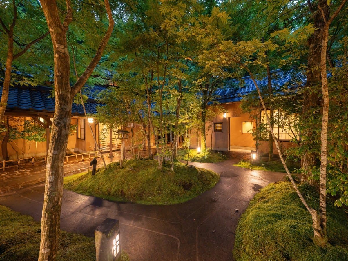 Lantern-lit garden at Oyado Nonohana glowing at dusk beside the wooden building