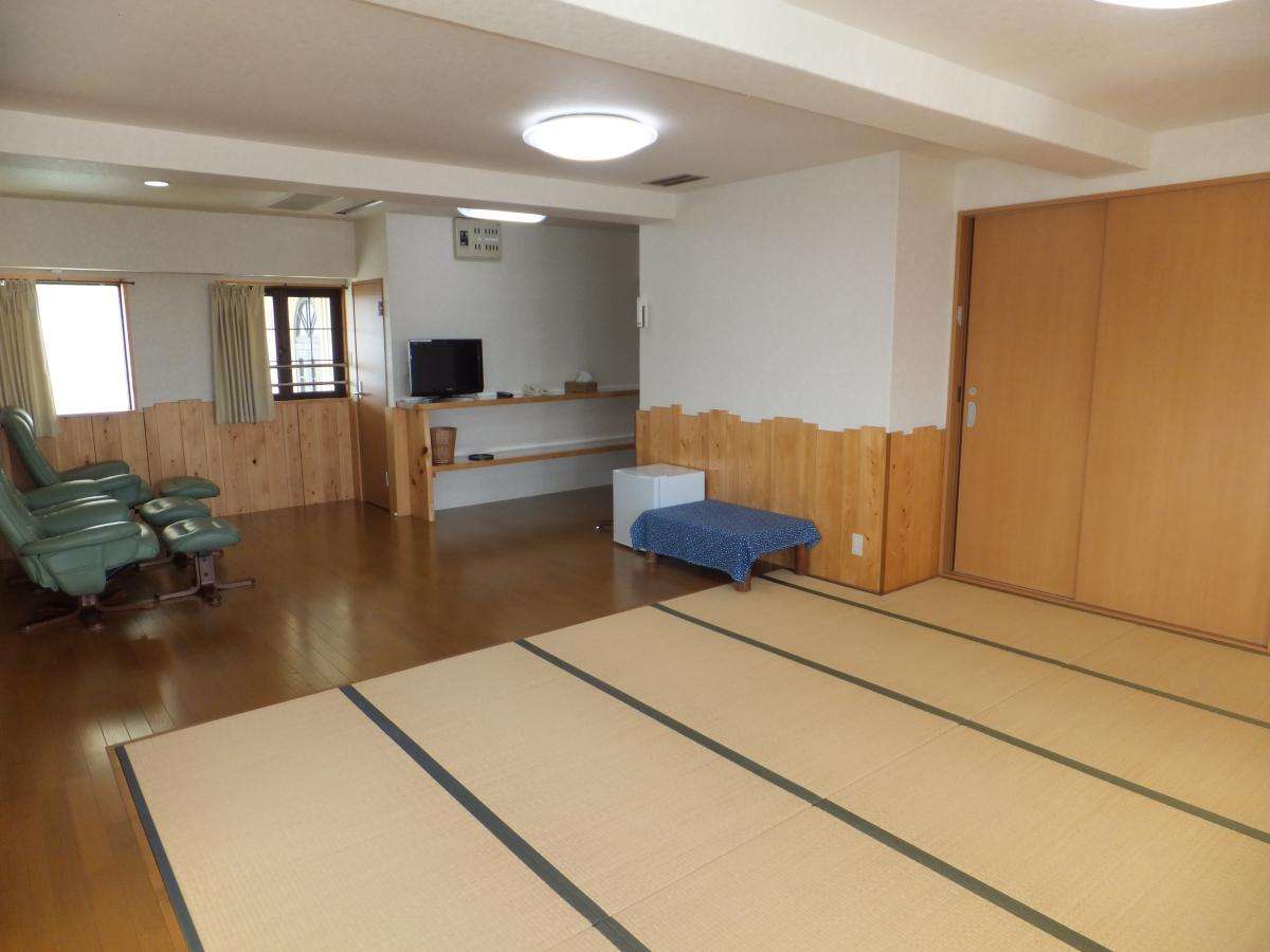 Spacious Japanese-style guest room at Fuji-no-en with tatami mats, wood-paneled walls, reclining chairs and a flat-screen TV