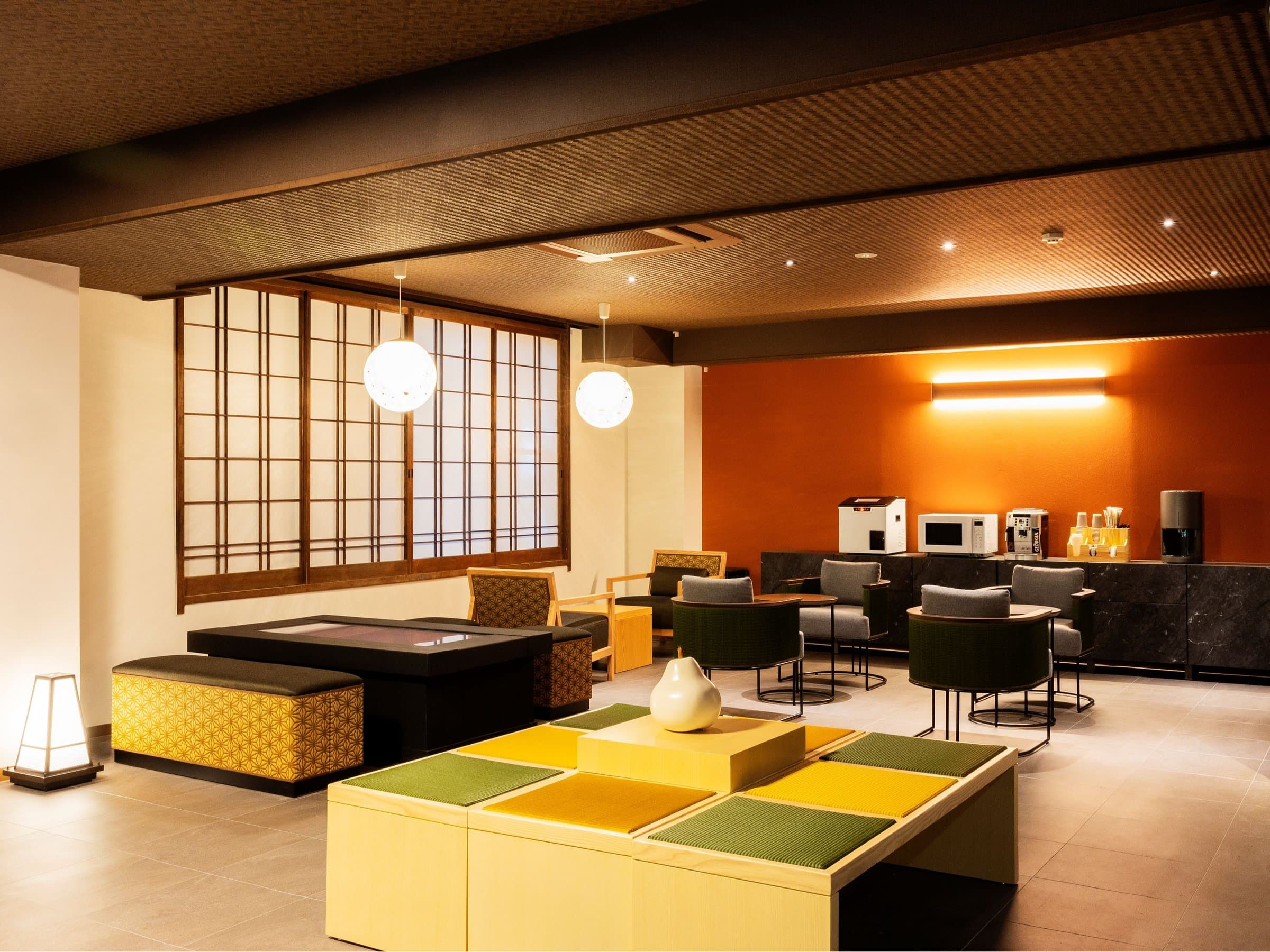 Guest lounge at Yusai Bekkan with sofas, low tables and paper-screened windows admitting soft daylight