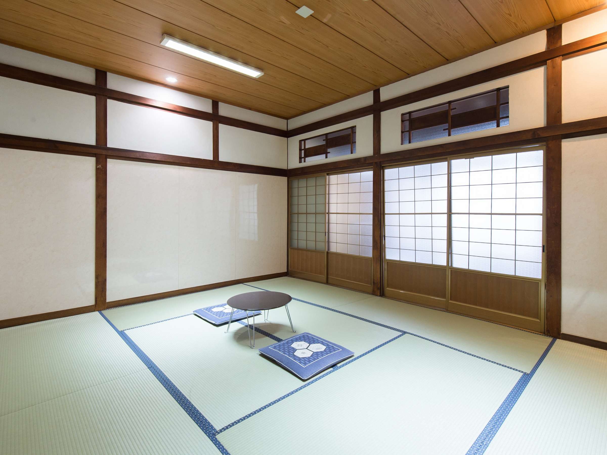 Spacious tatami guest room at Yamamoto Ryokan with shoji paper screens, wood ceiling and a low table