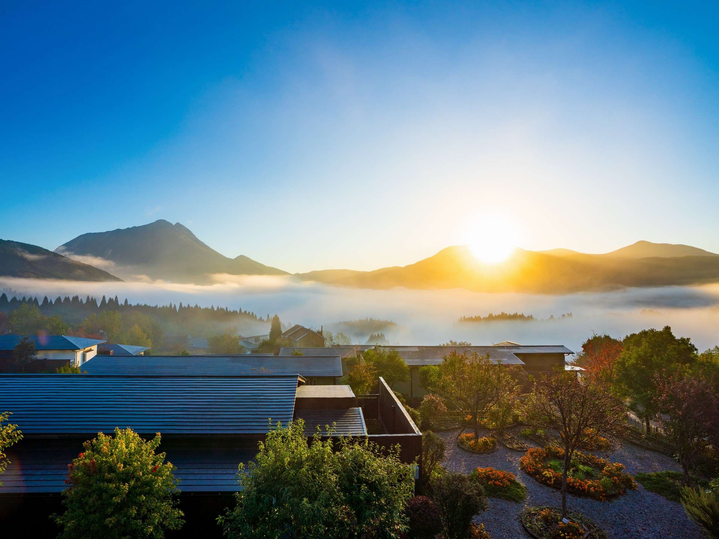 Yufuin Hanayoshi at sunrise above a sea of clouds with Mount Yufu rising over the Yufuin valley