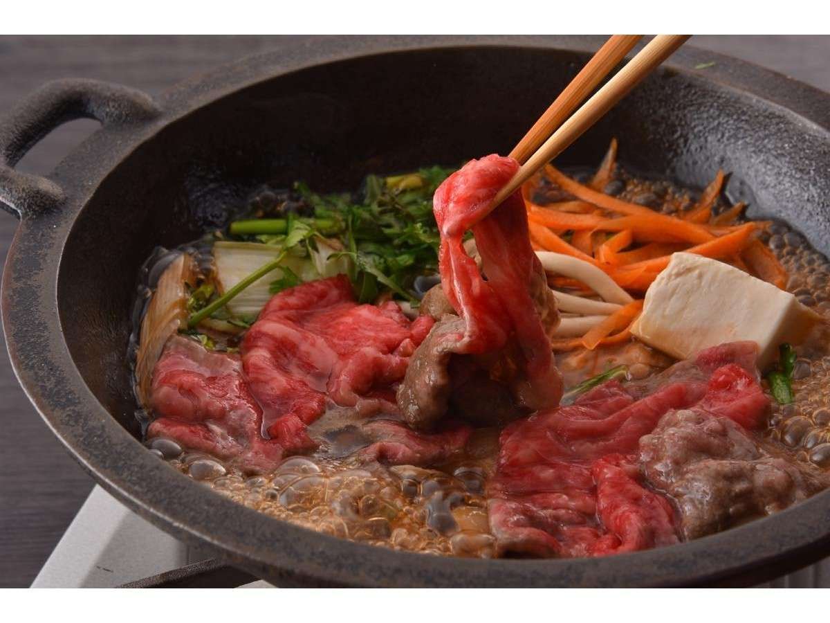 Marbled wagyu beef simmering in an iron sukiyaki pot at Okunikko Yuno-mori