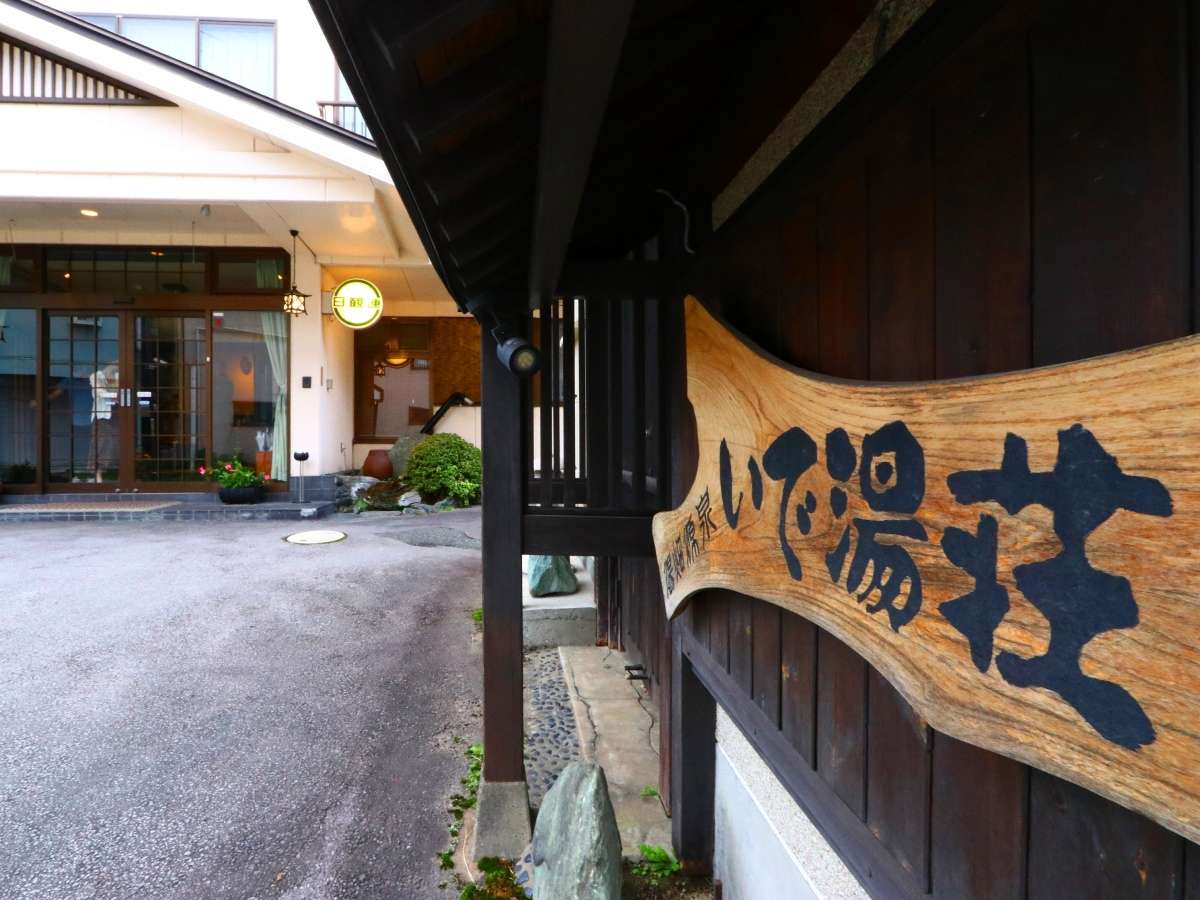 Inn entrance and front approach with a hand-carved wooden signboard beside the lantern-lit doorway
